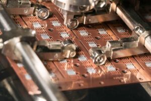 Close up epoxy stamping on lead frame in die attach machine in semiconductor manufacturing.