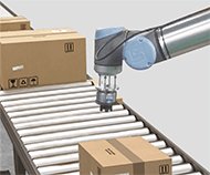 cardboard boxes on a conveyor being picking by a UR robot arm