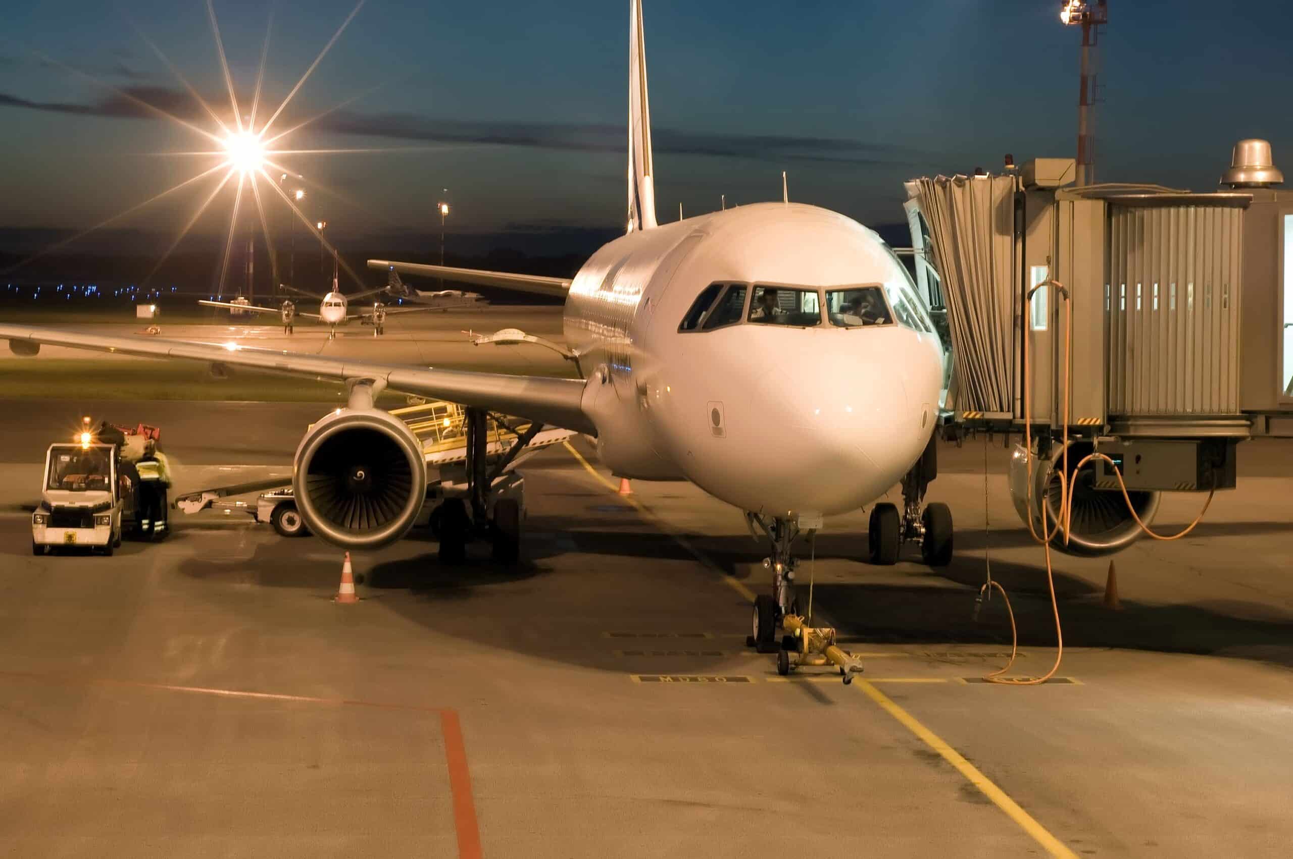 commercial airplane on apron at night connected to jet bridge