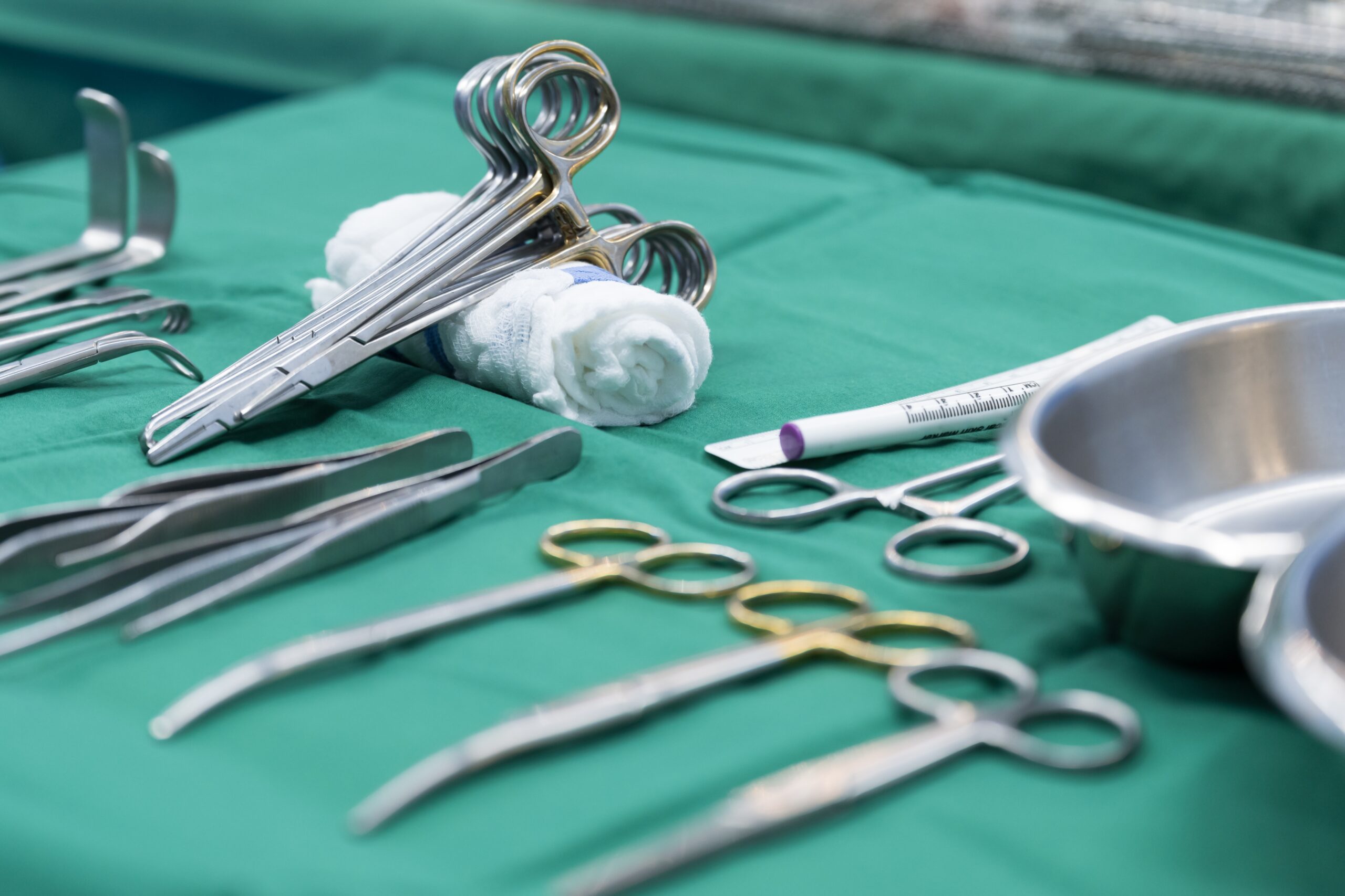 Surgical clamps and medical equipment on a green surgical tray inside operating room