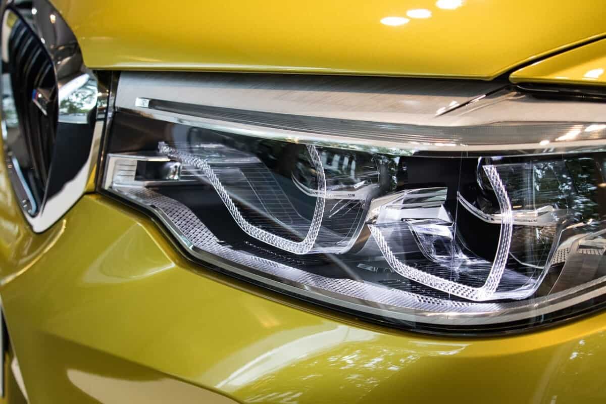 front car headlight on a metallic yellow car