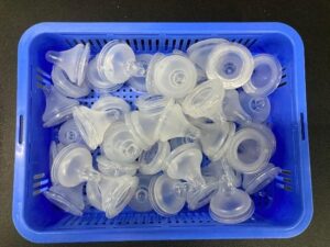 semi-transparent baby bottle nipples in a blue bin ready for bin picking