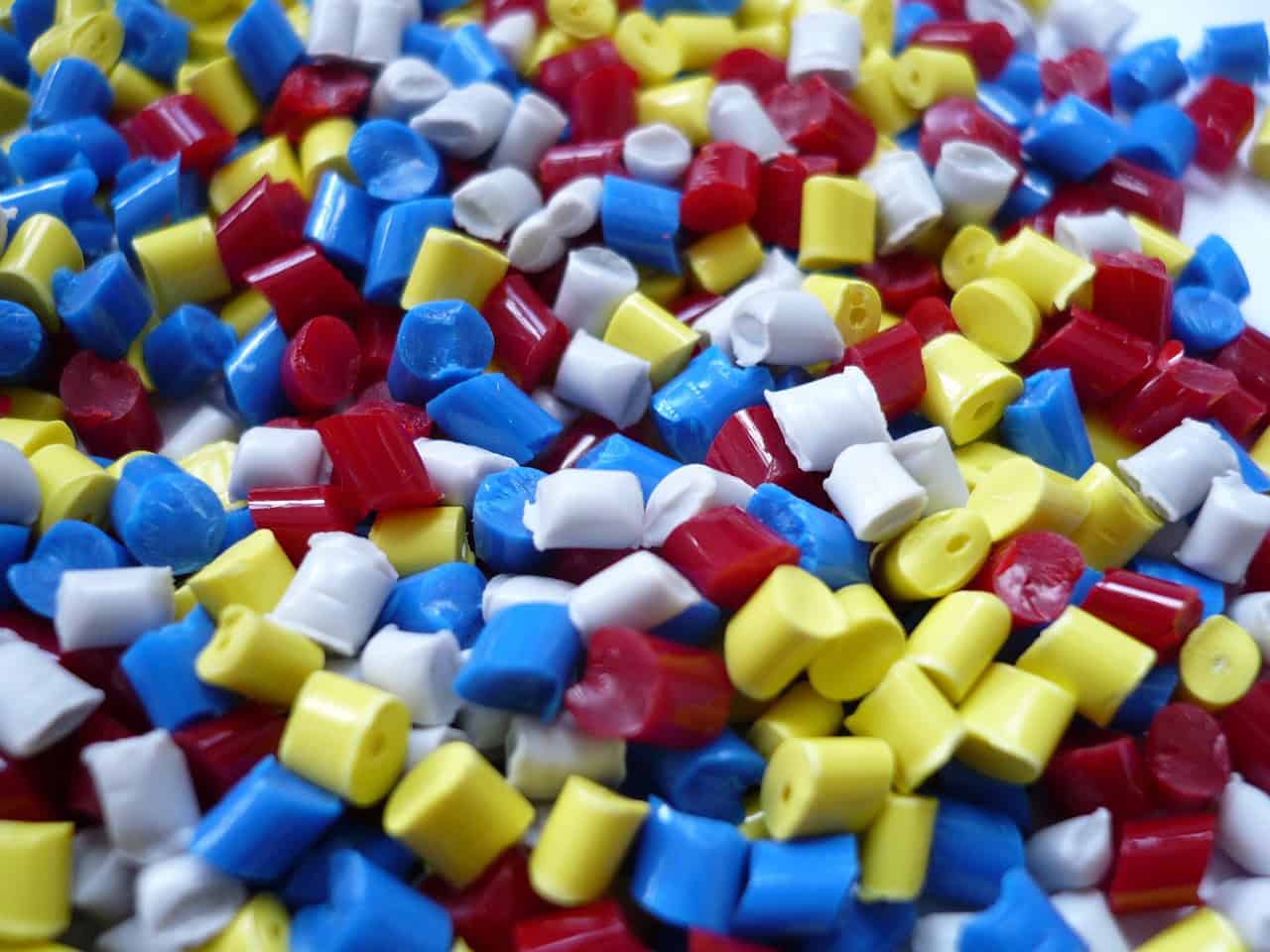 Plastic polymer granules blue, red, white, and yellow colored plastic polymer granules