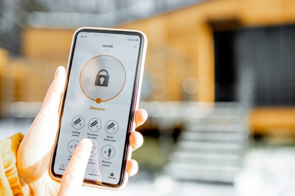 a person inside a smart factory holding a smartphone up with a padlock symbol on the screen