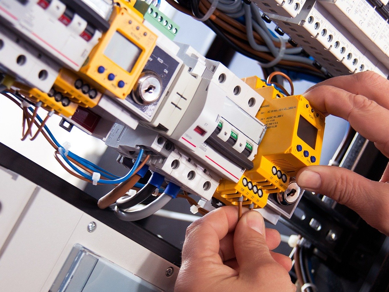 an electrician inspecting a wiring panel inside a smart factory