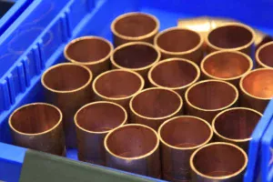 Unpolished cylindrical metal workpieces arranged in a bin for robotic CNC machine tending.