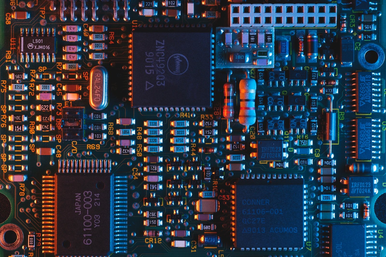 Close-up of a printed circuit board with integrated circuits, resistors, capacitors, and other electronic components.