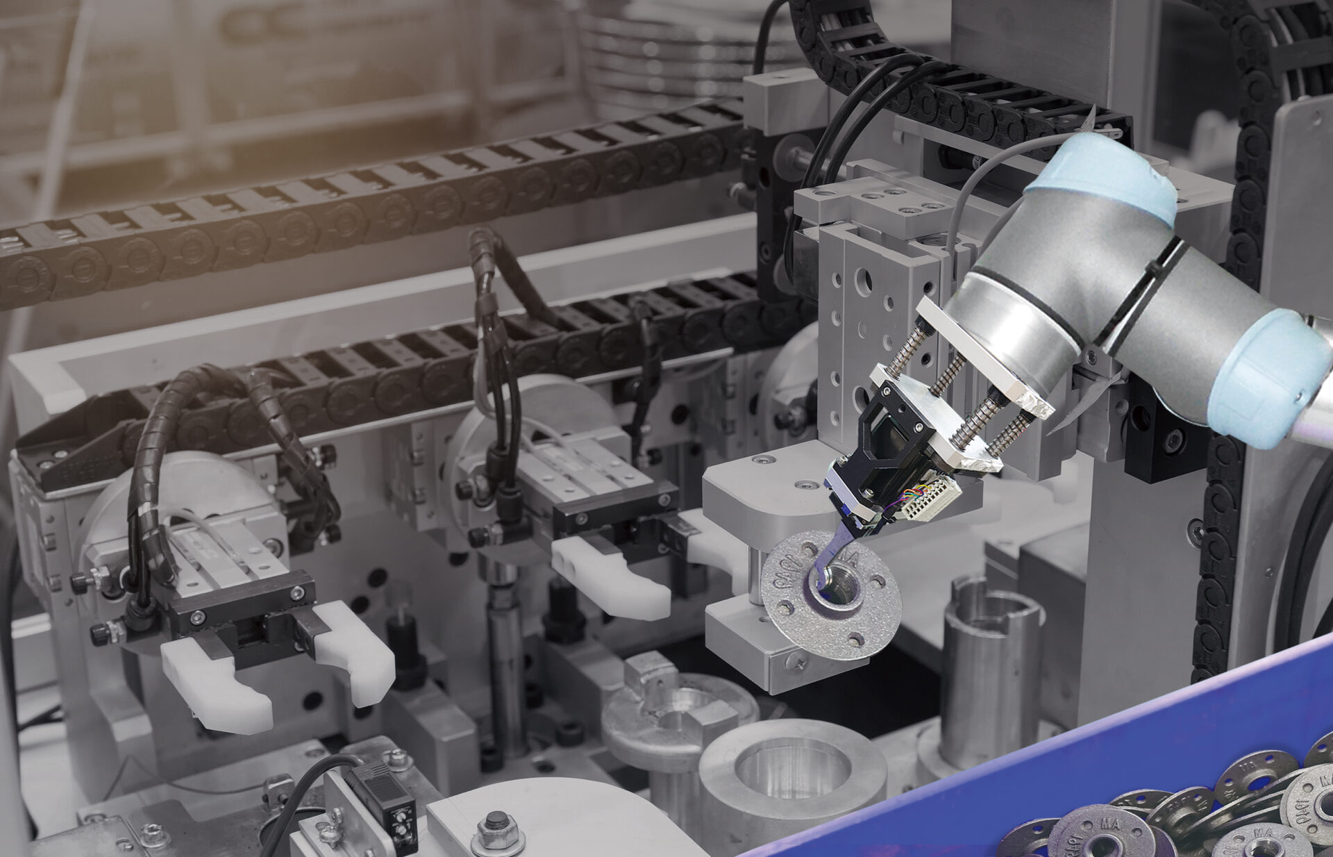 UR cobot performing automated machine tending (loading/unloading) of metal parts, guided by AccuPick AI vision software for high-precision placement in a manufacturing cell.