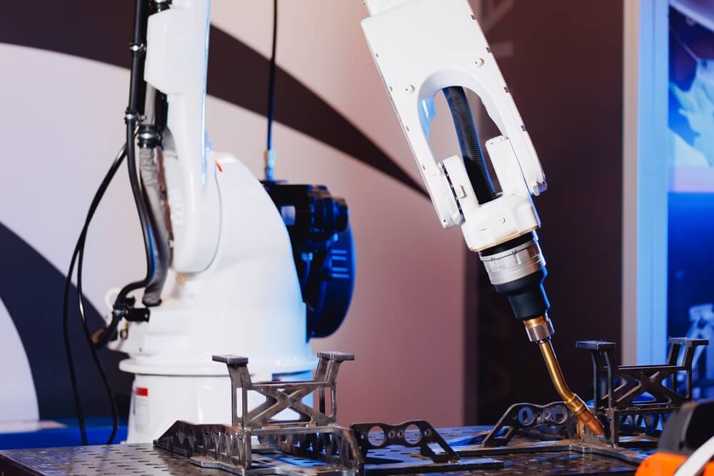 Industrial welding robot performing precision arc welding on metal fabrication, utilizing SolMotion vision guided robotics (VGR) software and AI vision for accurate path planning and quality welds.