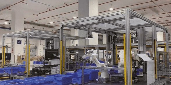 robot arms picking luxury items from blue bins inside a logistics hub