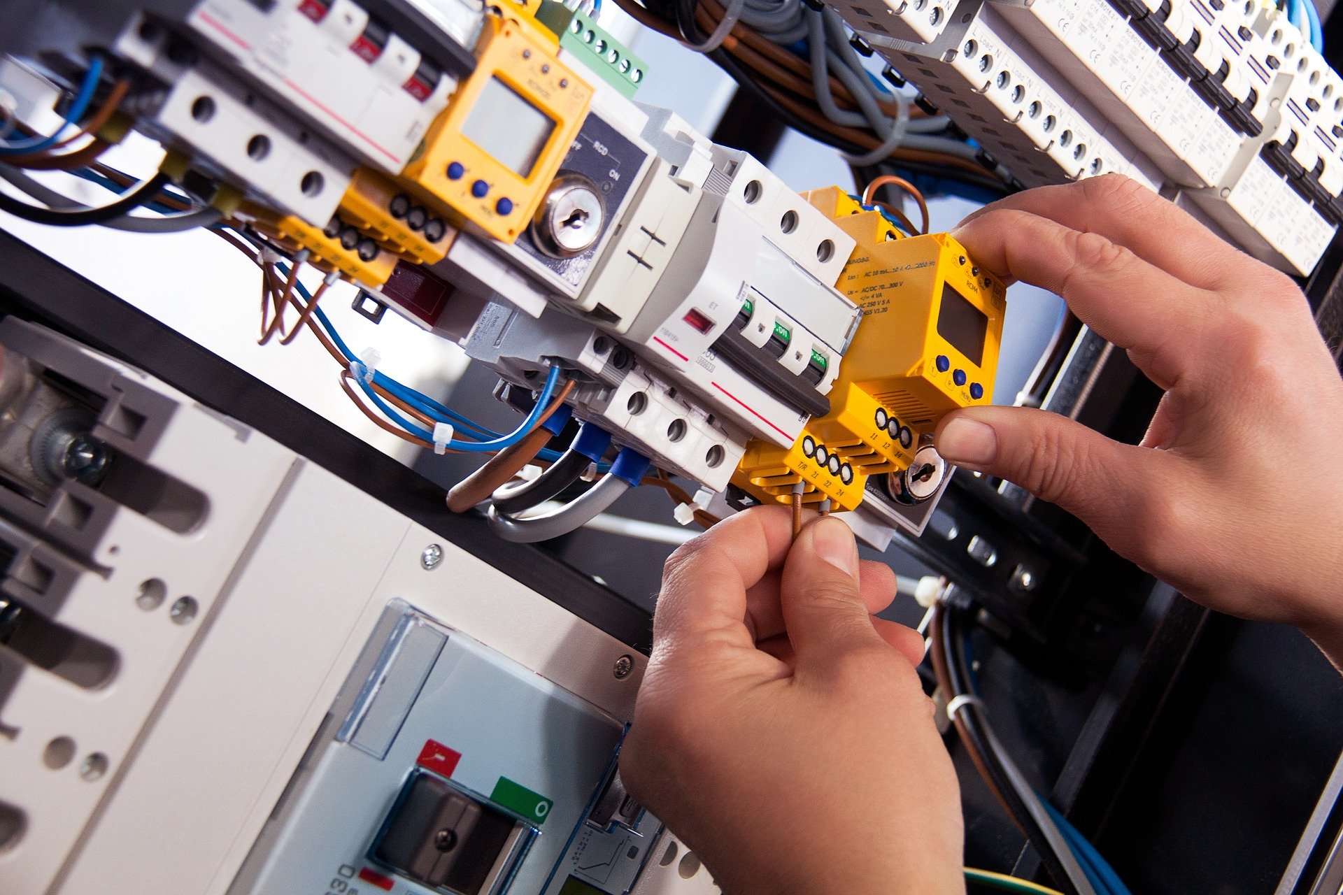 an electrician inspects complex machinery wiring in a smart factory