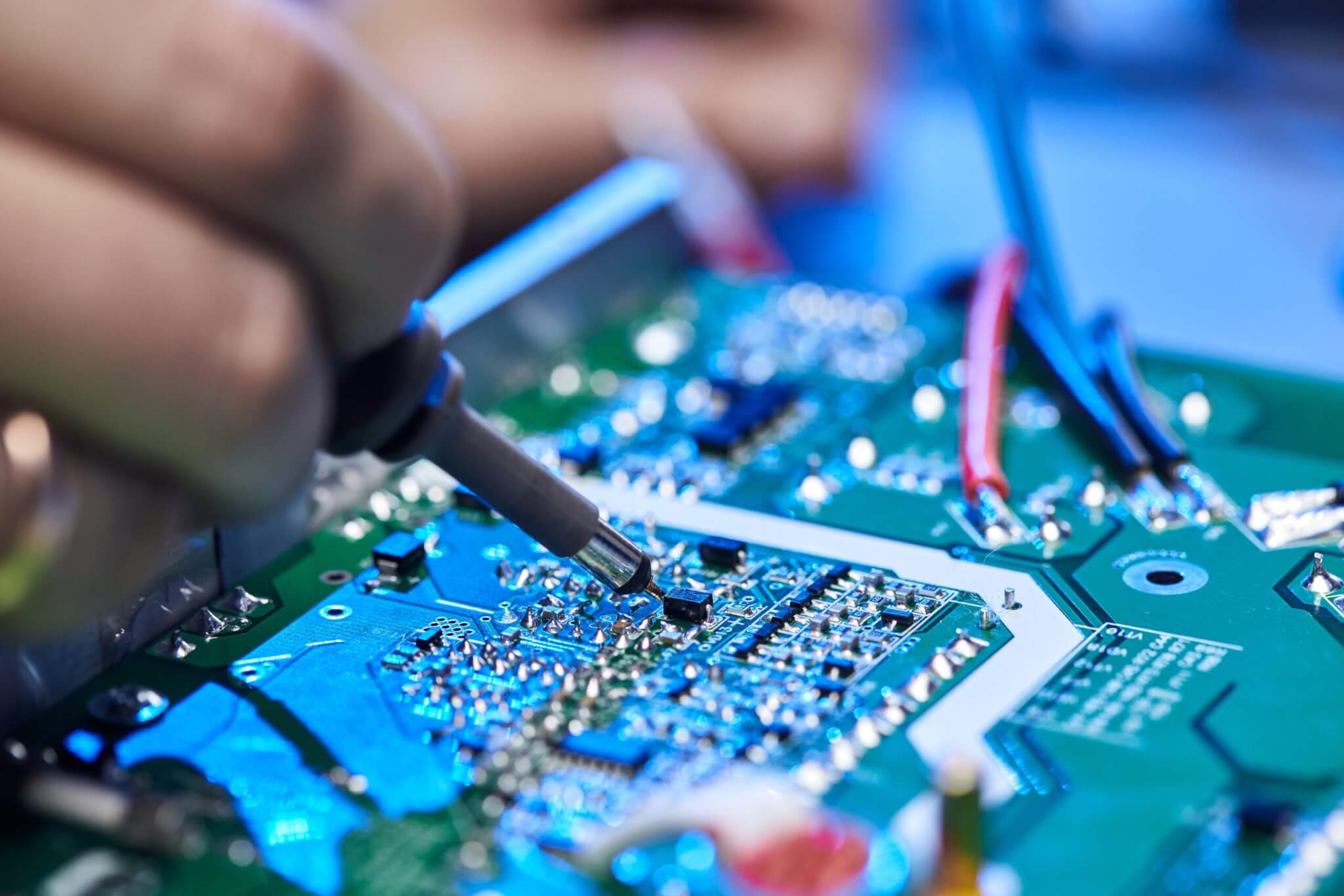 Technician works on electronic components during PCB assembly and inspection.