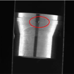 Vista de cerca de un componente mecanizado de precisión que muestra un defecto superficial localizado resaltado con un marcador circular de detección.