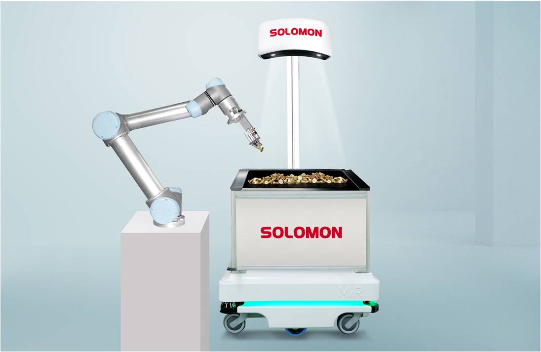 A Universal Robots collaborative robot arm using the Solomon AccuPick 3D vision system to perform random bin picking from a parts bin, which is mounted on an Autonomous Mobile Robot (AMR). A Solomon SolScan 3D scanner is mounted above the bin, illuminating the contents.