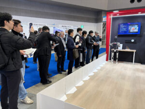 A crowd at iREX 2025 watches a Solomon humanoid robot powered by NVIDIA Jetson and Isaac GR00T. The robot uses AI vision to autonomously locate and grasp objects based on VLM instructions.