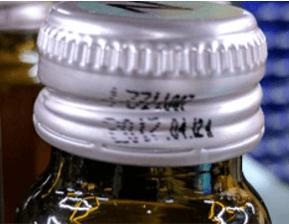 Skewed Text Example of skewed or distorted printed characters on bottle caps illustrating OCR readability issues.
