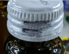 Smudged Text Example of smudged or partially unreadable characters on bottle cap printing used for OCR defect classification.