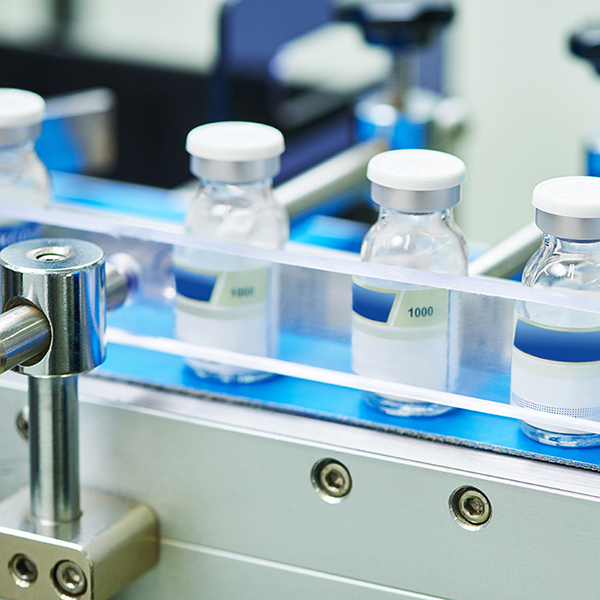 vials of medication are lined up on a conveyor belt